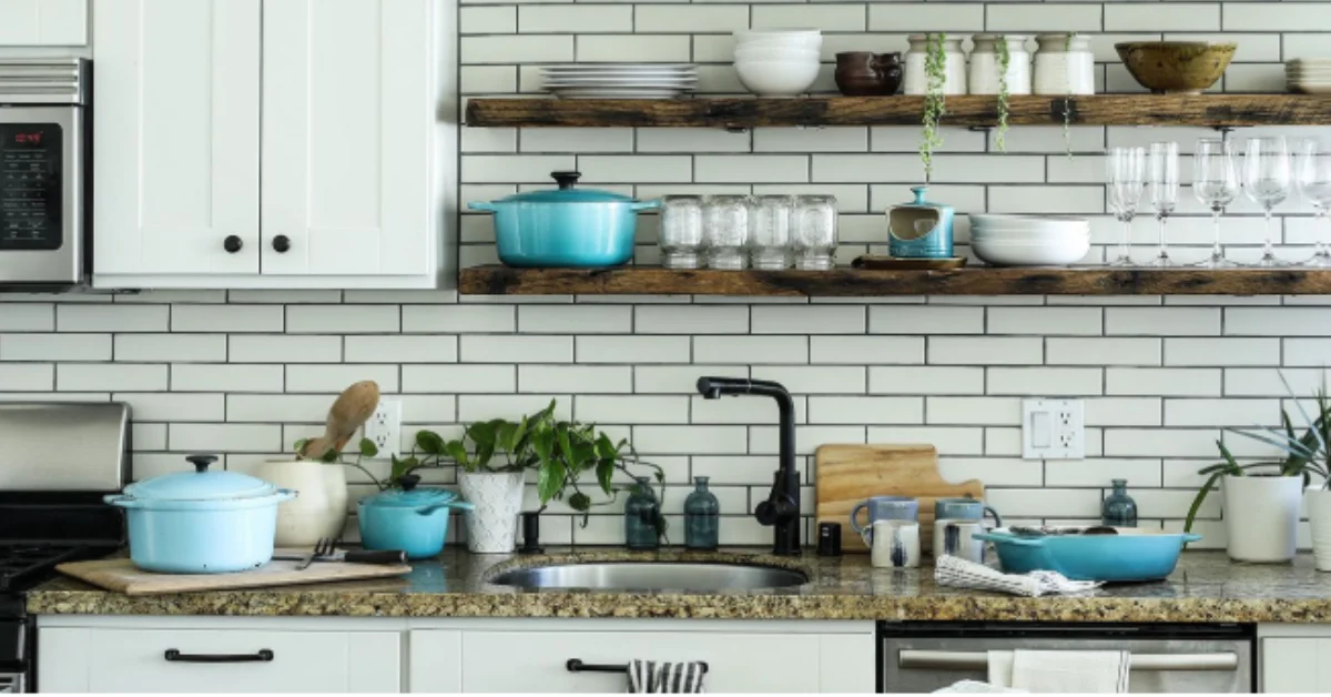 Kitchen tools arranged neatly on a modern kitchen countertop with shelves, plants, and cookware.