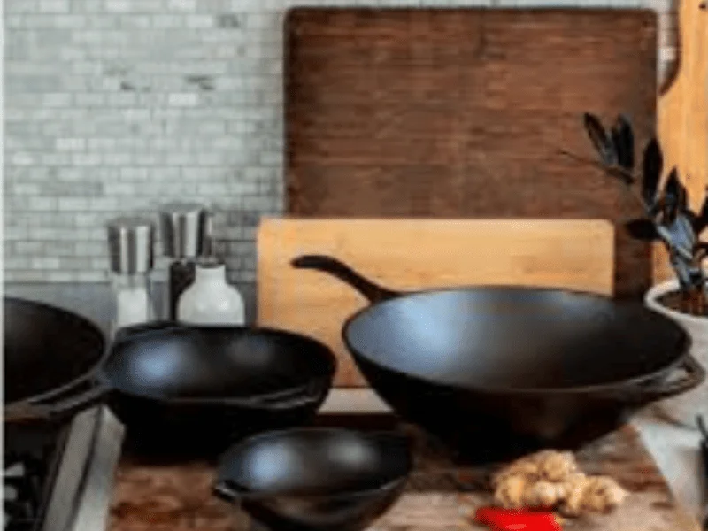 Wok and Pan cookware arranged neatly on a kitchen countertop with chopping boards and cooking essentials.