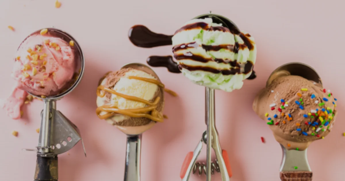 Ice cream scoop holding colorful, decorated ice cream scoops with toppings on a pink background.